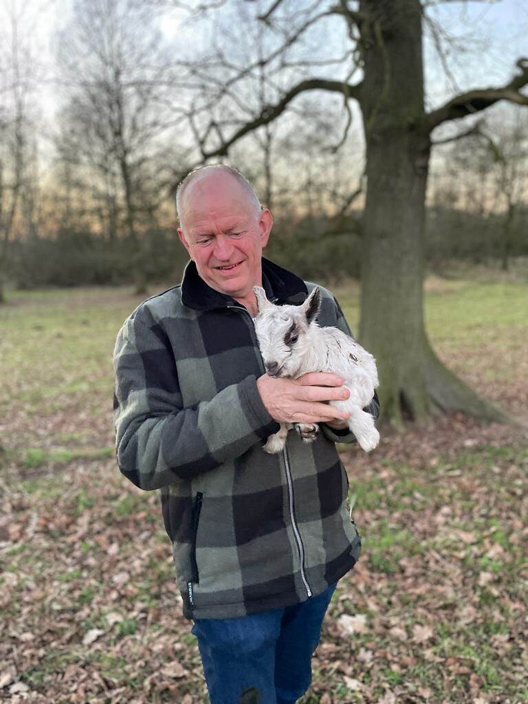 man met klein geitje op de arm